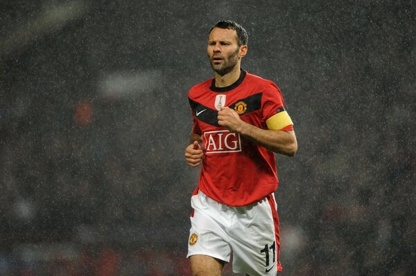 A football player in a red T-shirt and white shorts