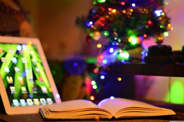 Un livre ouvert à côté d une tablette à Noël