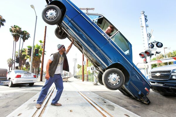 Hombre fuerte levanta coche con conductor