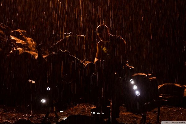 Силуэт мужчины, стоящего под дождем рядом с прожекторами