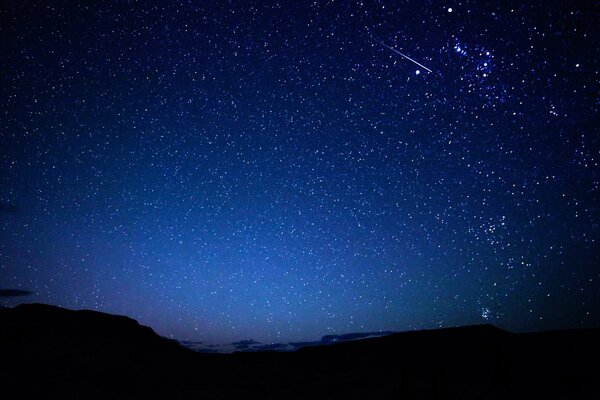 Cielo stellato e meteore sullo sfondo delle montagne