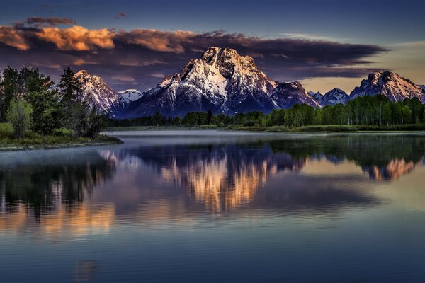 Verschneite Berge. See. Die Wolken