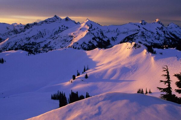 Montañas de invierno en la nieve al atardecer