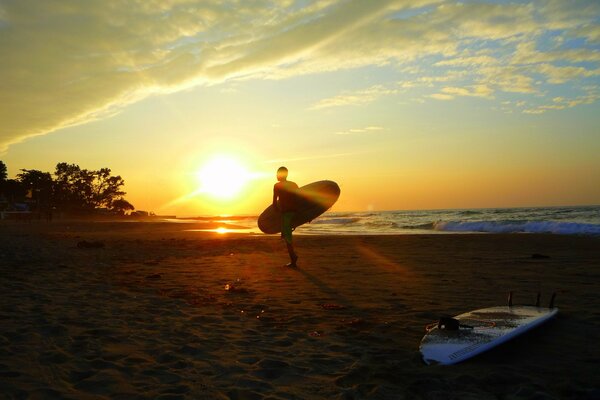 A guy rides a surfboard at dawn