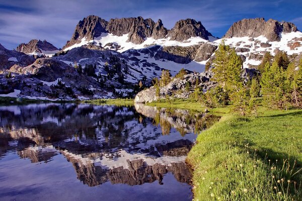 Sommer vor dem Hintergrund der schneebedeckten Gipfel der Berge und des Sees