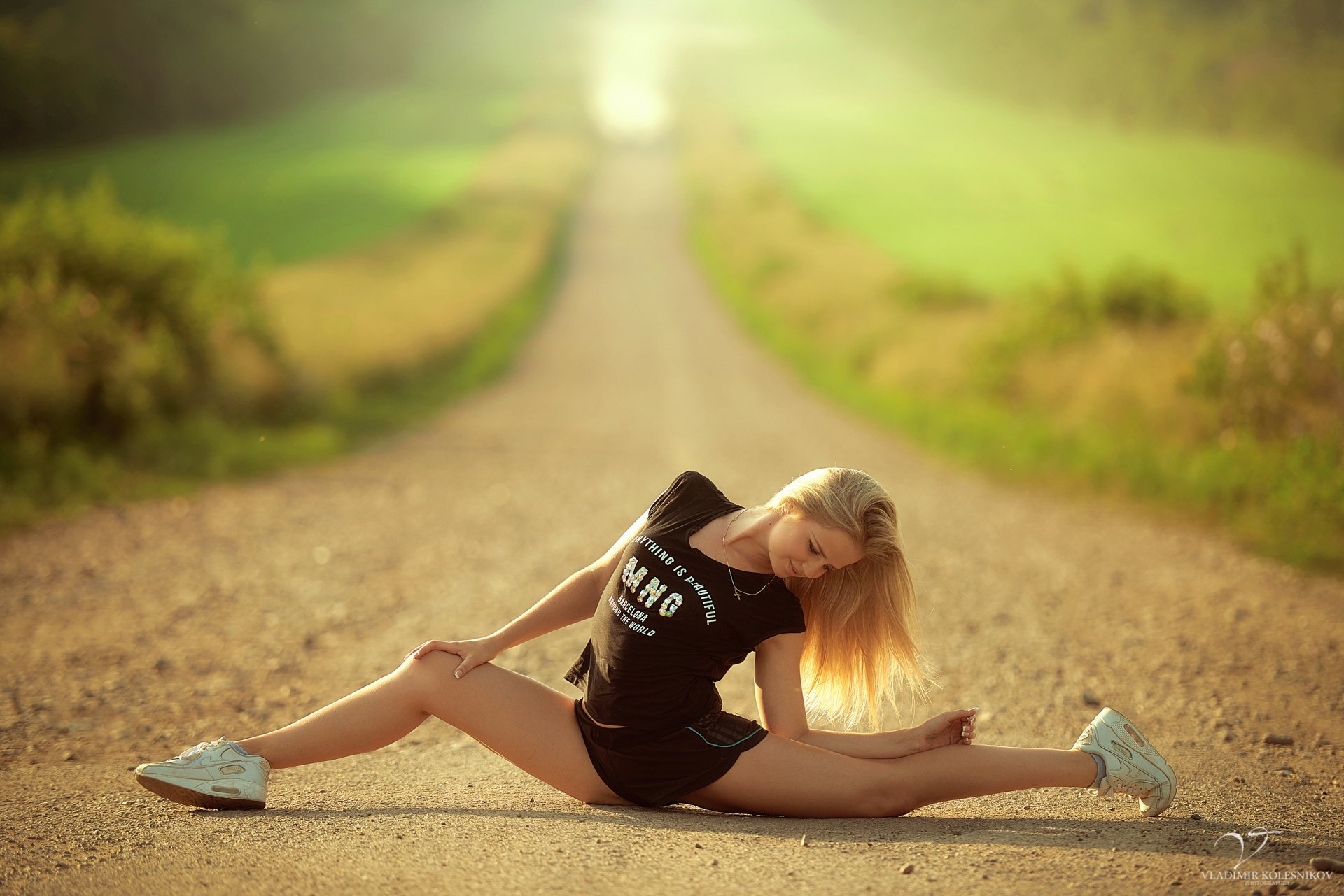 lim sports girl blonde village in the middle road pose stretching twine flexibility t-shirt shorts shoes sun green blur