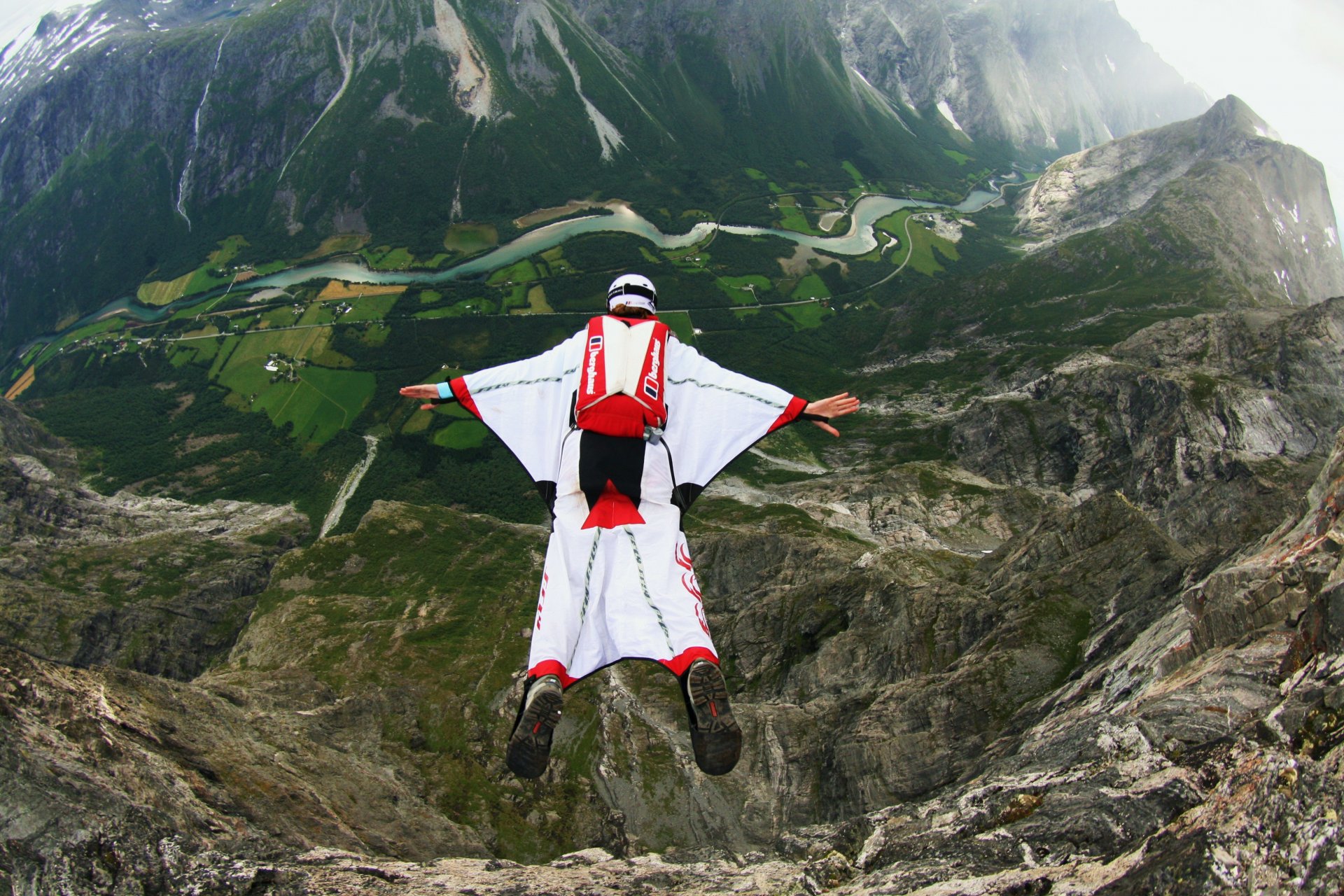 traje de alas piloto salto base casco montañas valles ríos noruega contenedor paracaídas deportes extremos