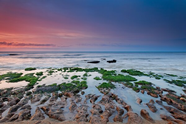 Der Himmel ist in verschiedenen Farben gefärbt und die Riffe im Meer