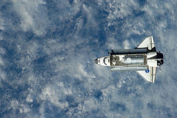 Shuttle in space above the Earth and clouds