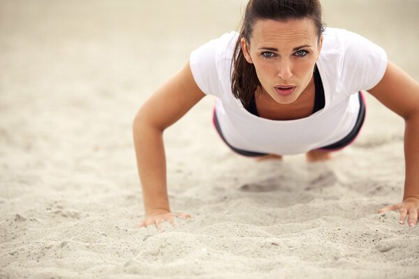 Femme faisant des pompes sur le sable