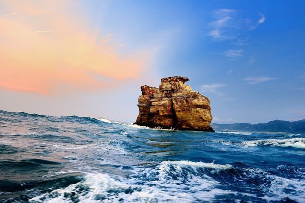 Una roca solitaria entre las olas del mar azul