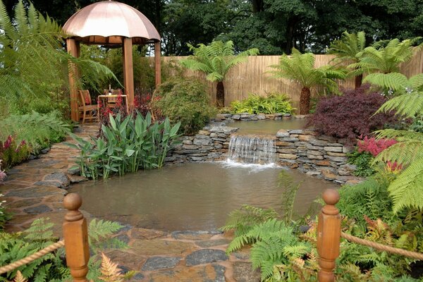 Gazebo dans le jardin avec étang et cascade