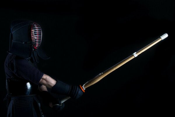 A kendo fighter in a black uniform is ready to fight