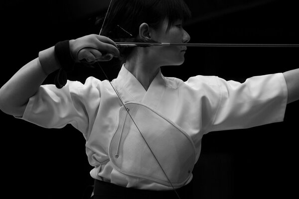 Chica japonesa en ropa blanca dispara un arco
