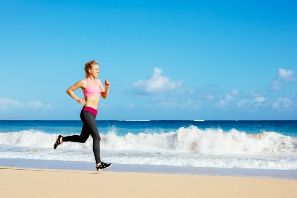 Chica deportiva corriendo en la playa de arena