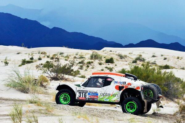 Buggy blanco en las arenas del Rally Dakar 2014 con ruedas verdes