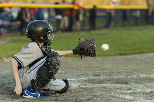 Сидит на поле мальчик бейсболист
