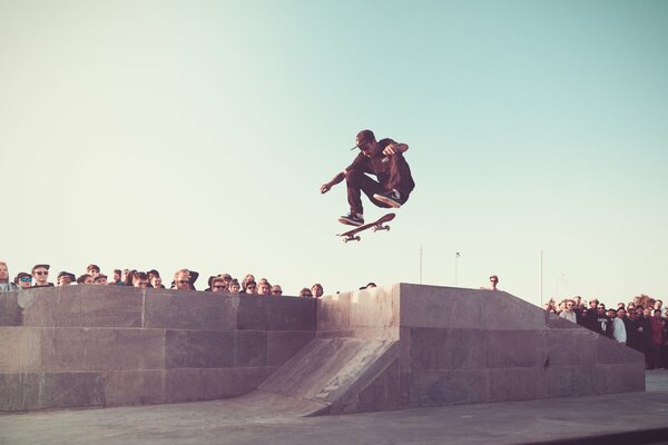 La foule regarde comme un skateboarder fait un saut