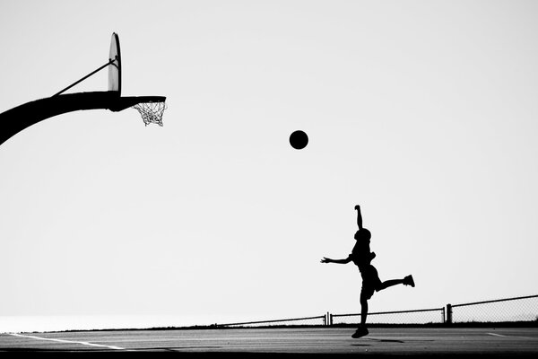 Silhouette of a girl throwing a ball into the ring