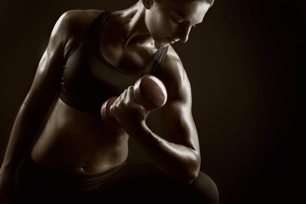 A woman trains her hands with dumbbells