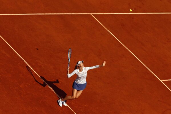 Sharapova con una raqueta de tenis lanza la pelota bajo el sol