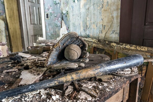 Ein Baseballschläger, ein Handschuh und ein Ball in einem zerstörten Haus