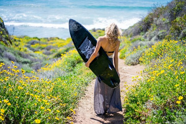 Ragazza con il surf sulla riva del mare