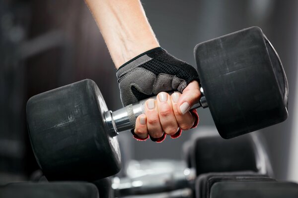 A woman in a glove lifts a dumbbell