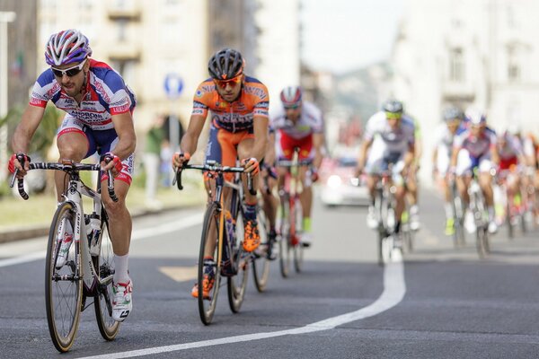 Bike race in the city. Athletes cyclists wallpaper