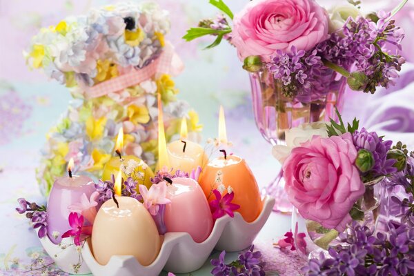 Burning Easter candles near a vase of flowers