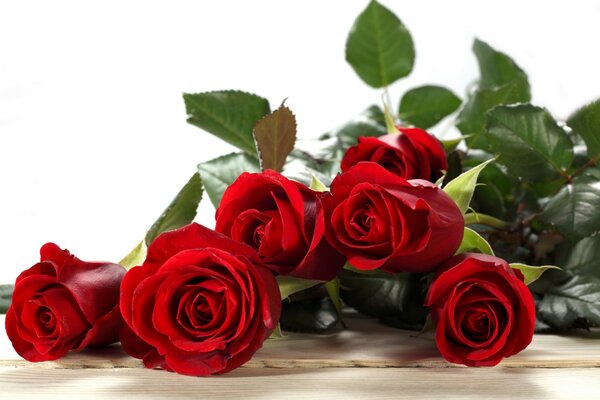 На столе лежит букет красных роз