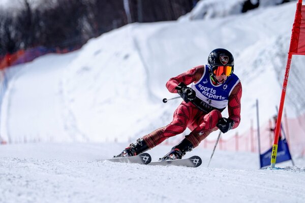 Ein Skifahrer im roten Anzug rast über die verschneite Strecke