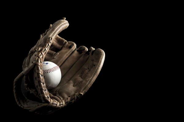 Ball im Baseballhandschuh auf schwarzem Hintergrund