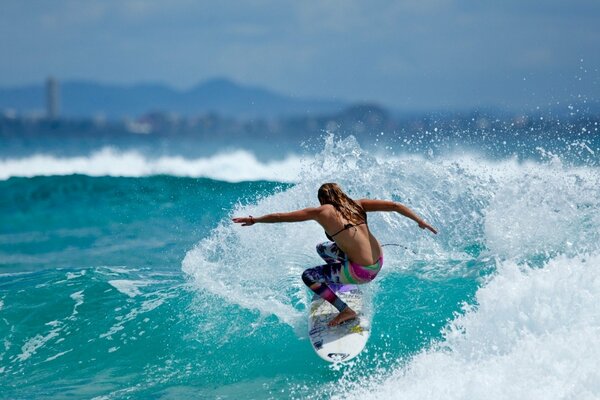 Fille sur le surf nage sur la vague