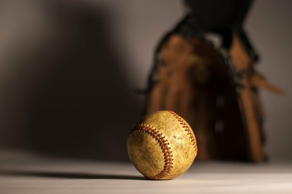 A baseball on the table and a glove