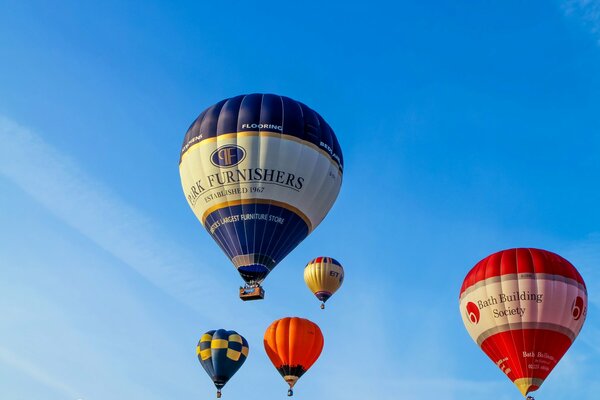 Cinque palloncini colorati volano attraverso il cielo blu