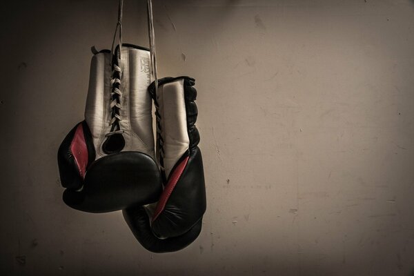 Boxhandschuhe hängen vor dem Hintergrund einer grauen Wand