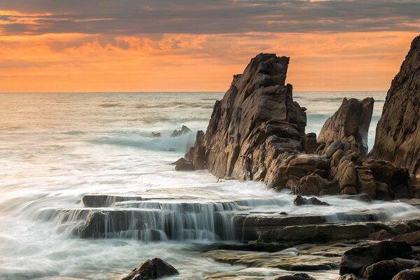 Rocas afiladas en el mar al atardecer