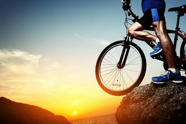 Mann mit Fahrrad steht auf einem Berg