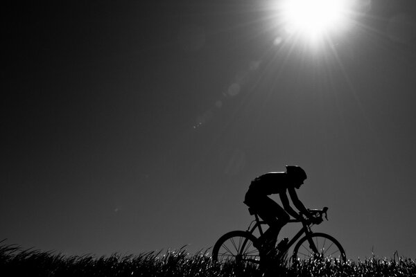 Radfahrer unter der hellen Abendsonne. Schwarz-Weiß-Foto eines Radfahrers