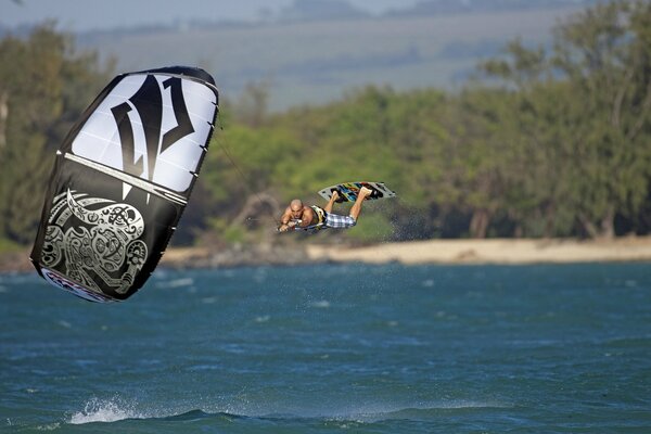 Surfer fliegt über das Meer und hält sich an einem Fallschirm fest