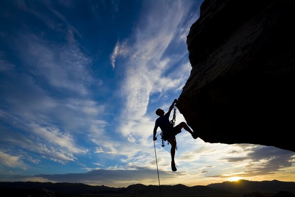 Silhouette of a climber against the blue sky and the setting sun