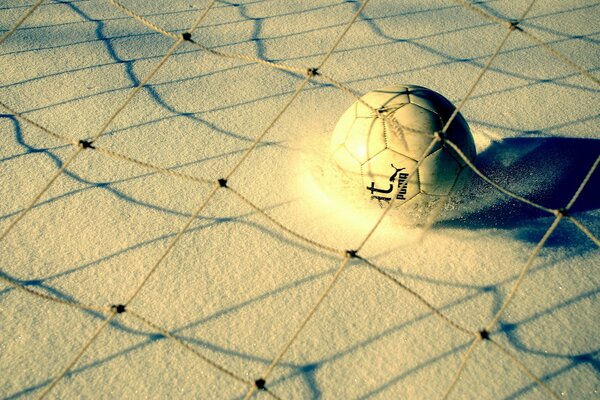 Ball im Sand unter dem Netz in Gelbtönen