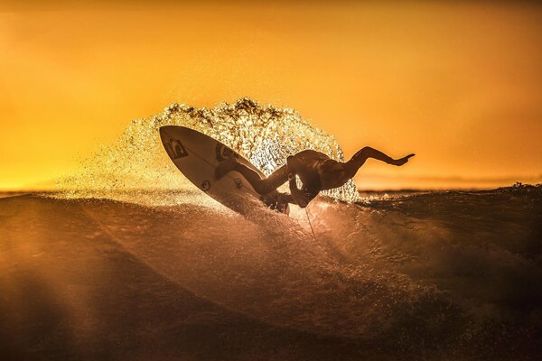 Серфинг на закате спортсмен ловит волну