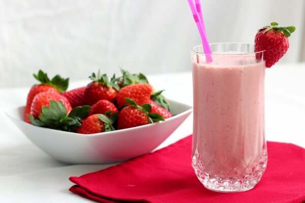 A glass of berry cocktail and a plate of strawberries