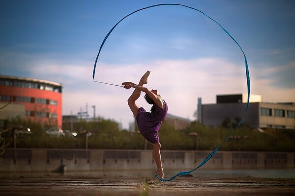 Gymnast with a ribbon on the background of the morning sky