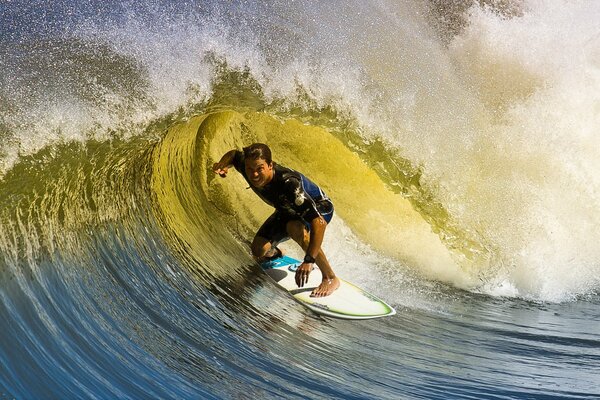 Surfista alegre en la tabla atrapando una gran ola