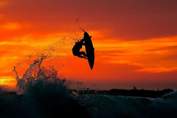 Surfista che vola su un onda al tramonto Hawk