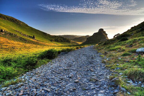 Rocky road between green hills