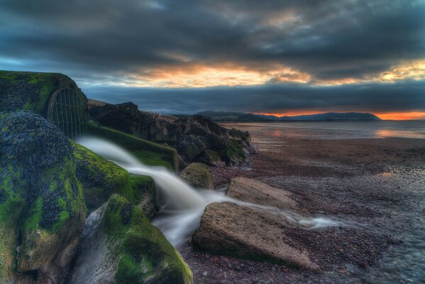 Landscape sea shore sunset and green stones